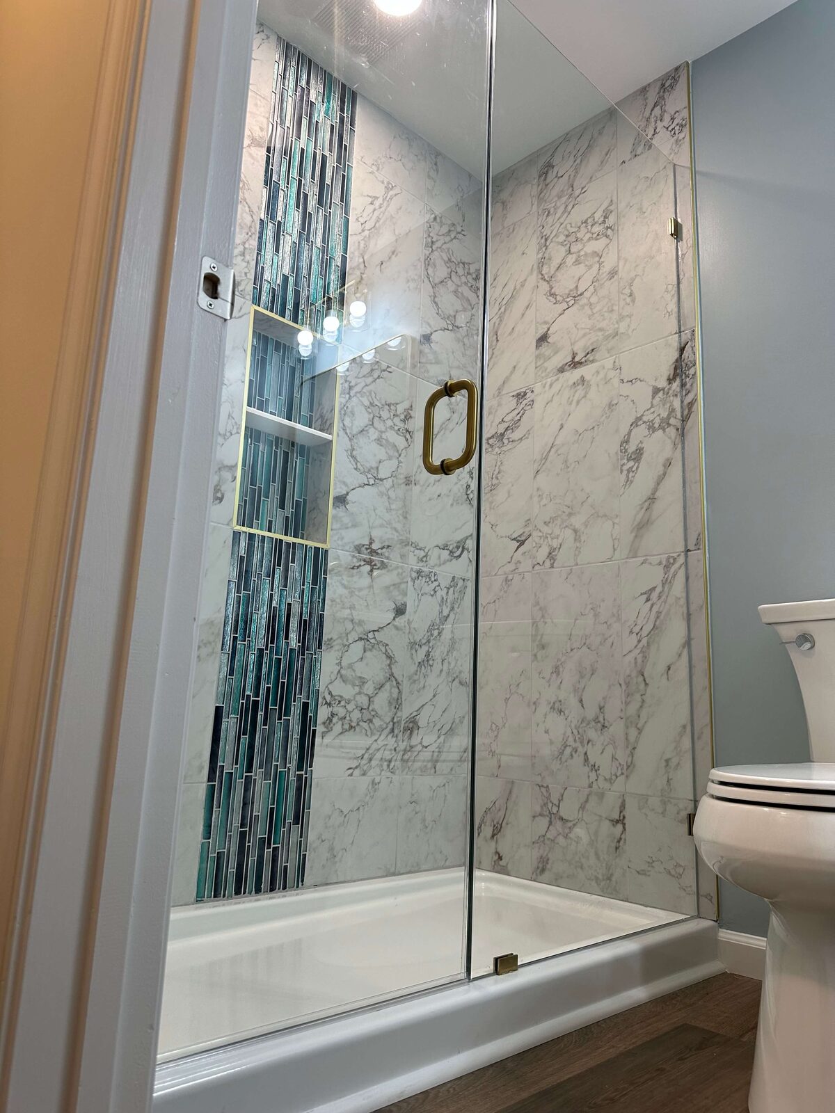 Basement bathroom with marble tile shower and glass tile waterfall accent