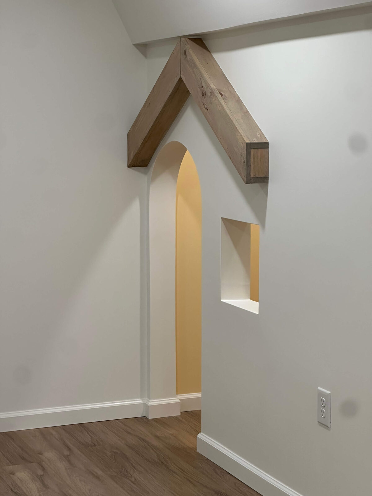 Custom built-in playhouse with arched opening and reclaimed wood beam