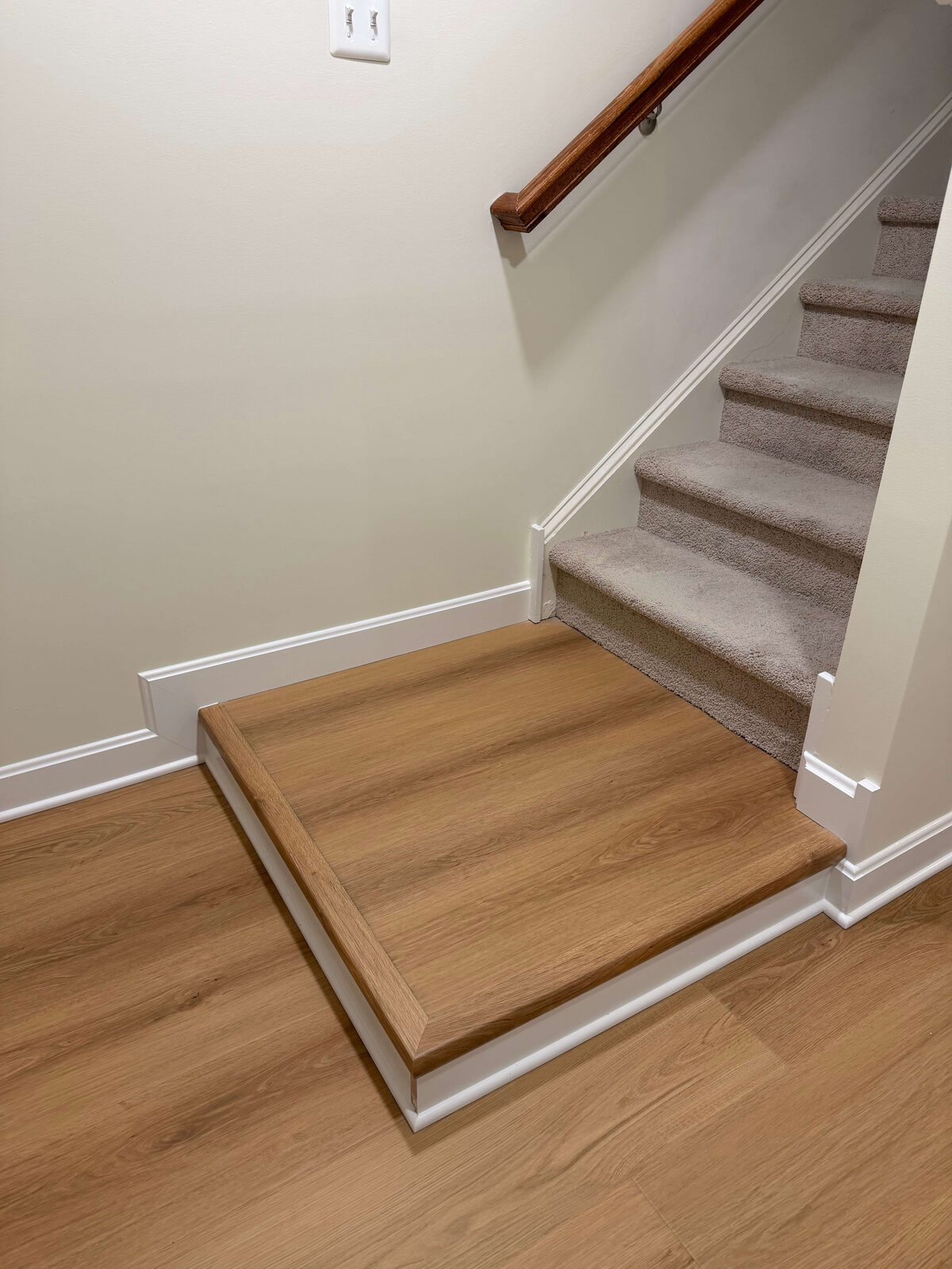 Refinished basement stair landing with LVP transition and clean baseboards