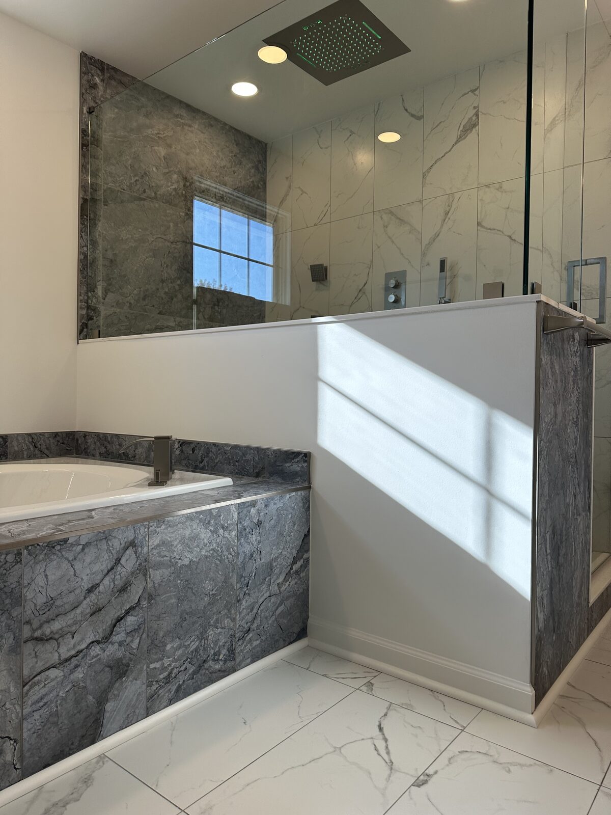 Tub corner with grey marble tile and matching shower walls