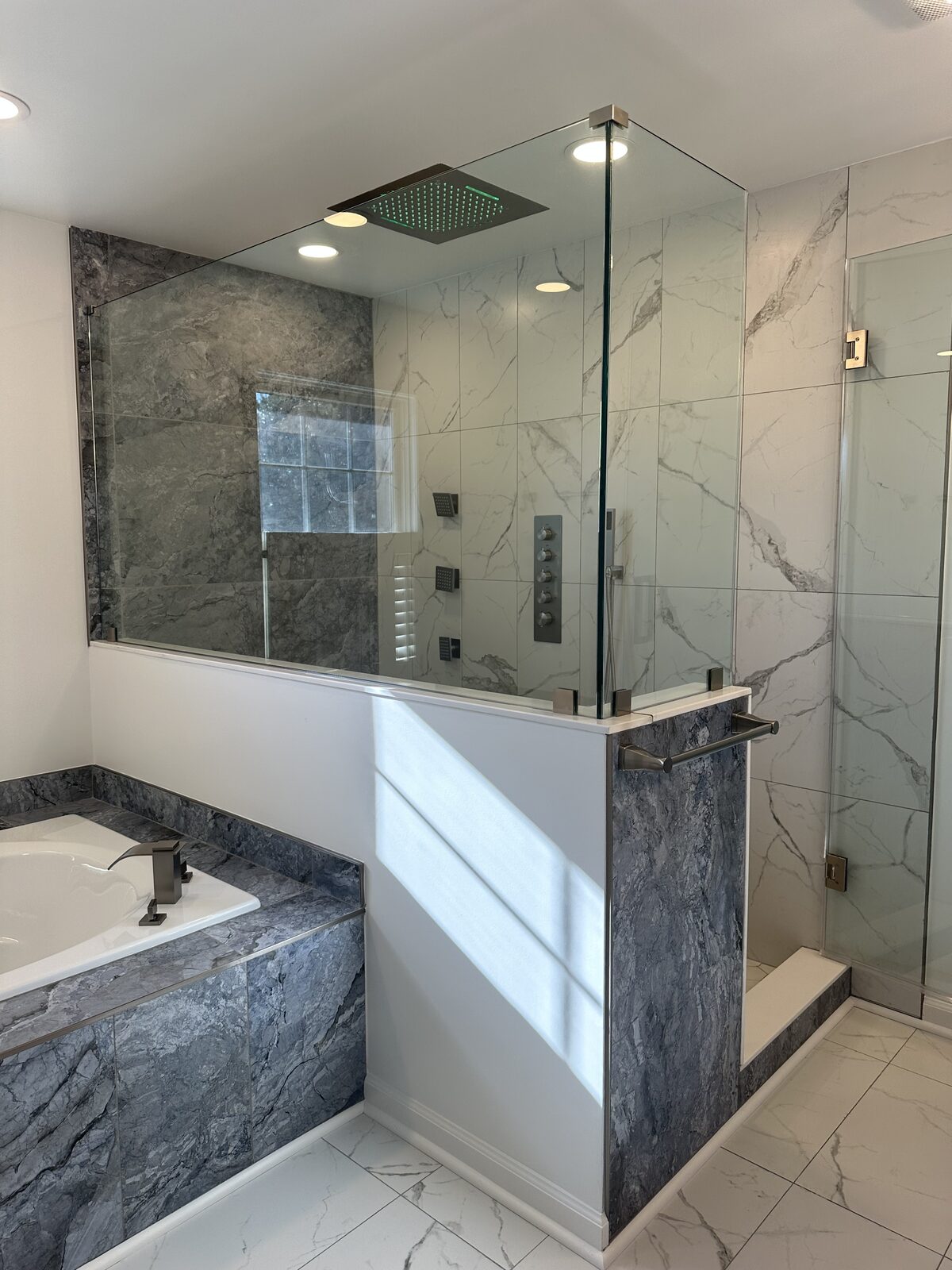 Master bath shower enclosure with marble walls and LED ceiling rain head