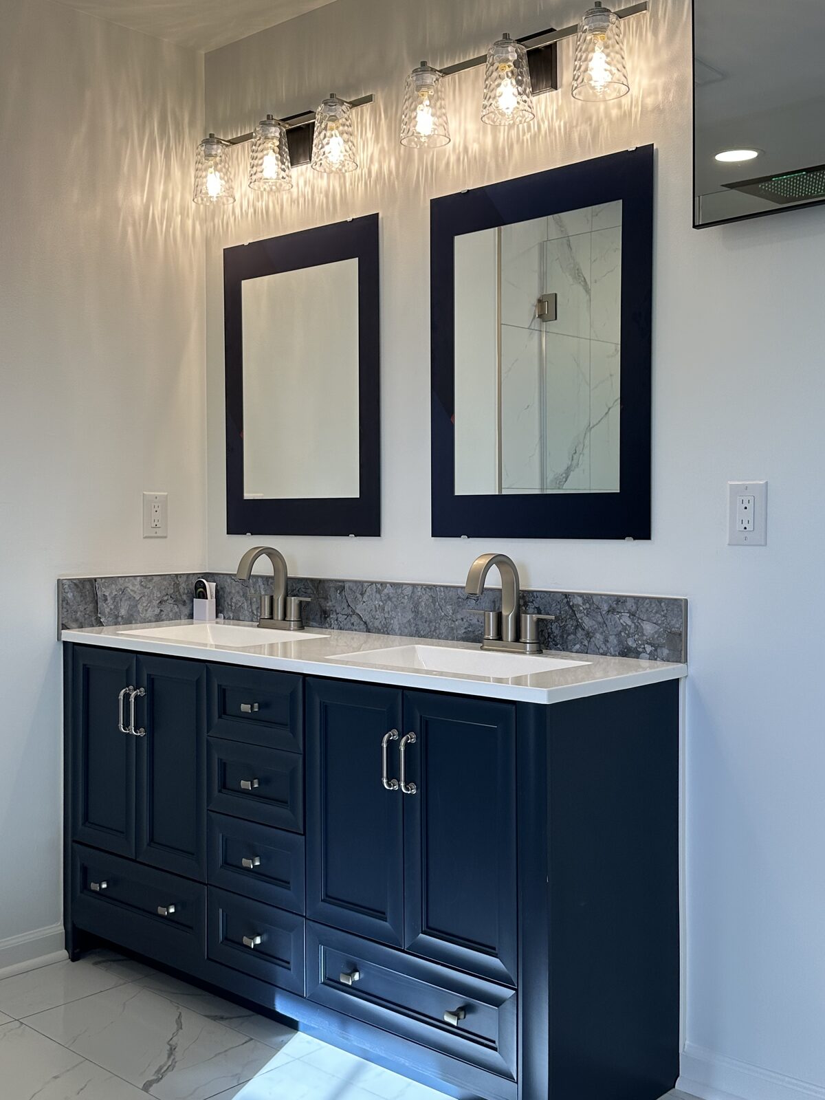 Navy double vanity with quartz top and crystal pendant lighting