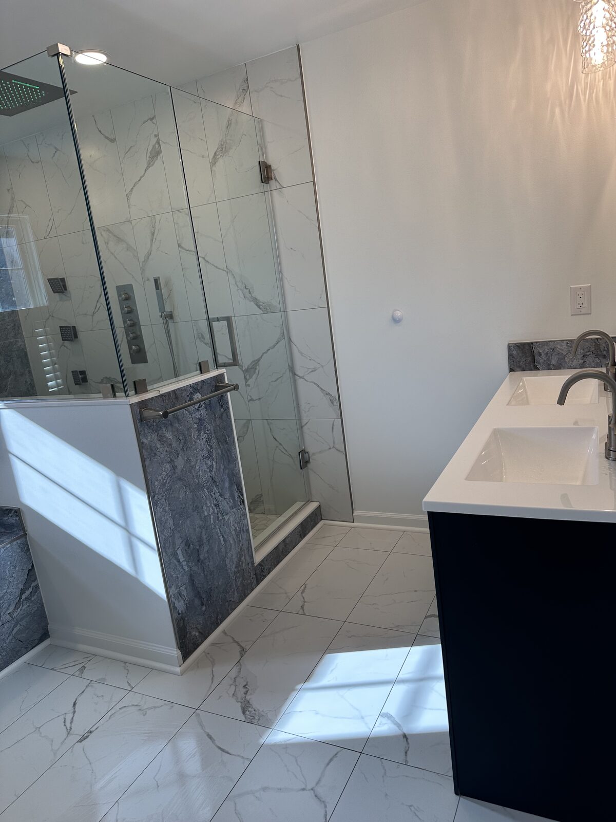 Wide bath view with marble shower and navy double vanity