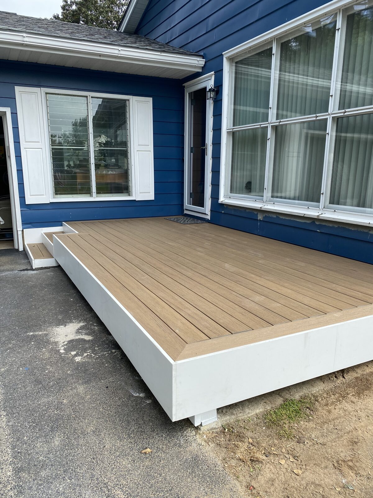 Composite deck with white PVC trim attached to navy blue home